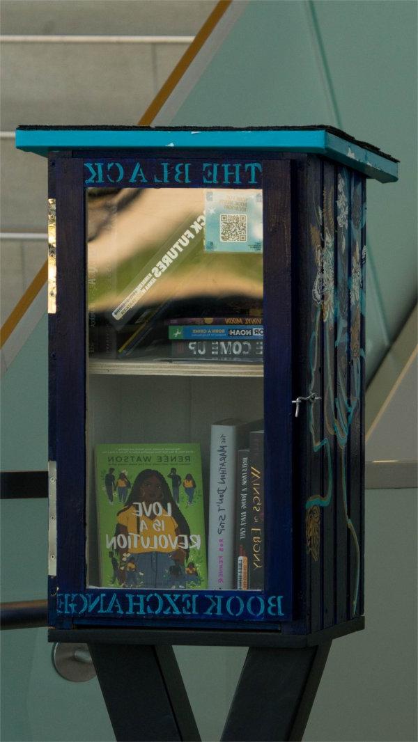 blue book box next to a staircase, The Black Book Exchange painted in light blue letters